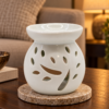Kleine weiße Keramik-Duftlampe mit Baummotiv in einer warm beleuchteten Wohnszene