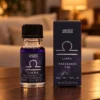 Sternzeichen-Duftöl Waage · 10 ml in einer warm beleuchteten Wohnszene auf dunklem Holz.